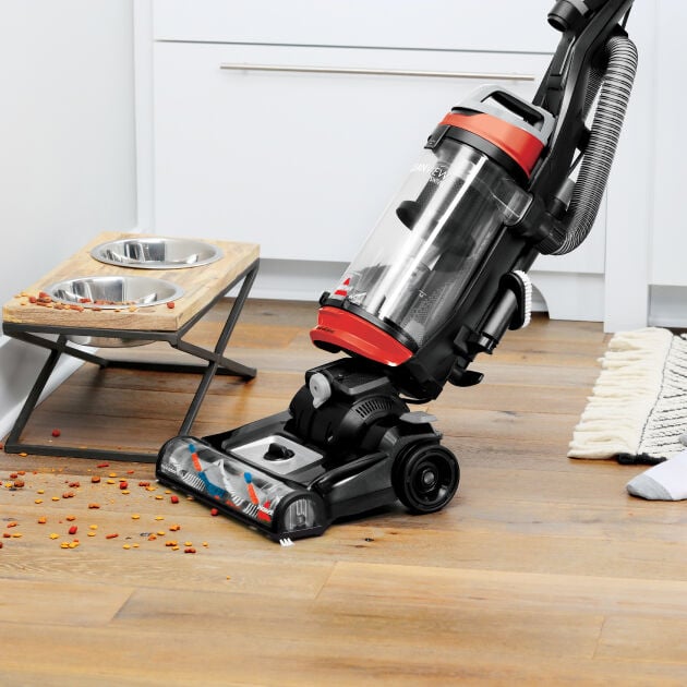 Woman using CleanView Swivel Pet Vac Scatter-Free technology to clean up dog food without scattering it