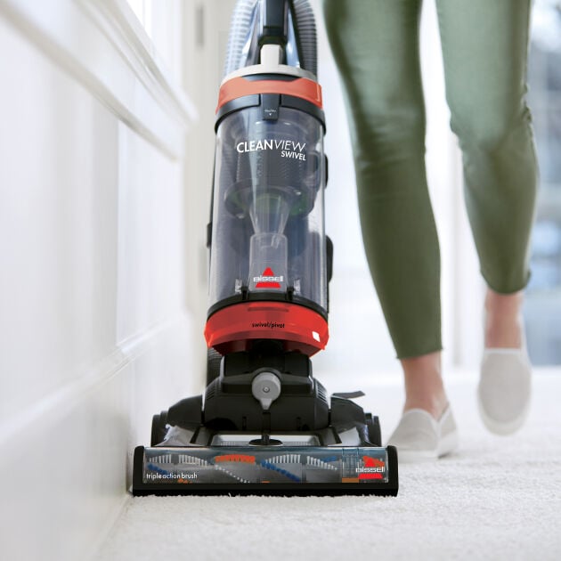 Woman using CleanView Swivel Pet Vac to clean right up to edge of carpet next to wall